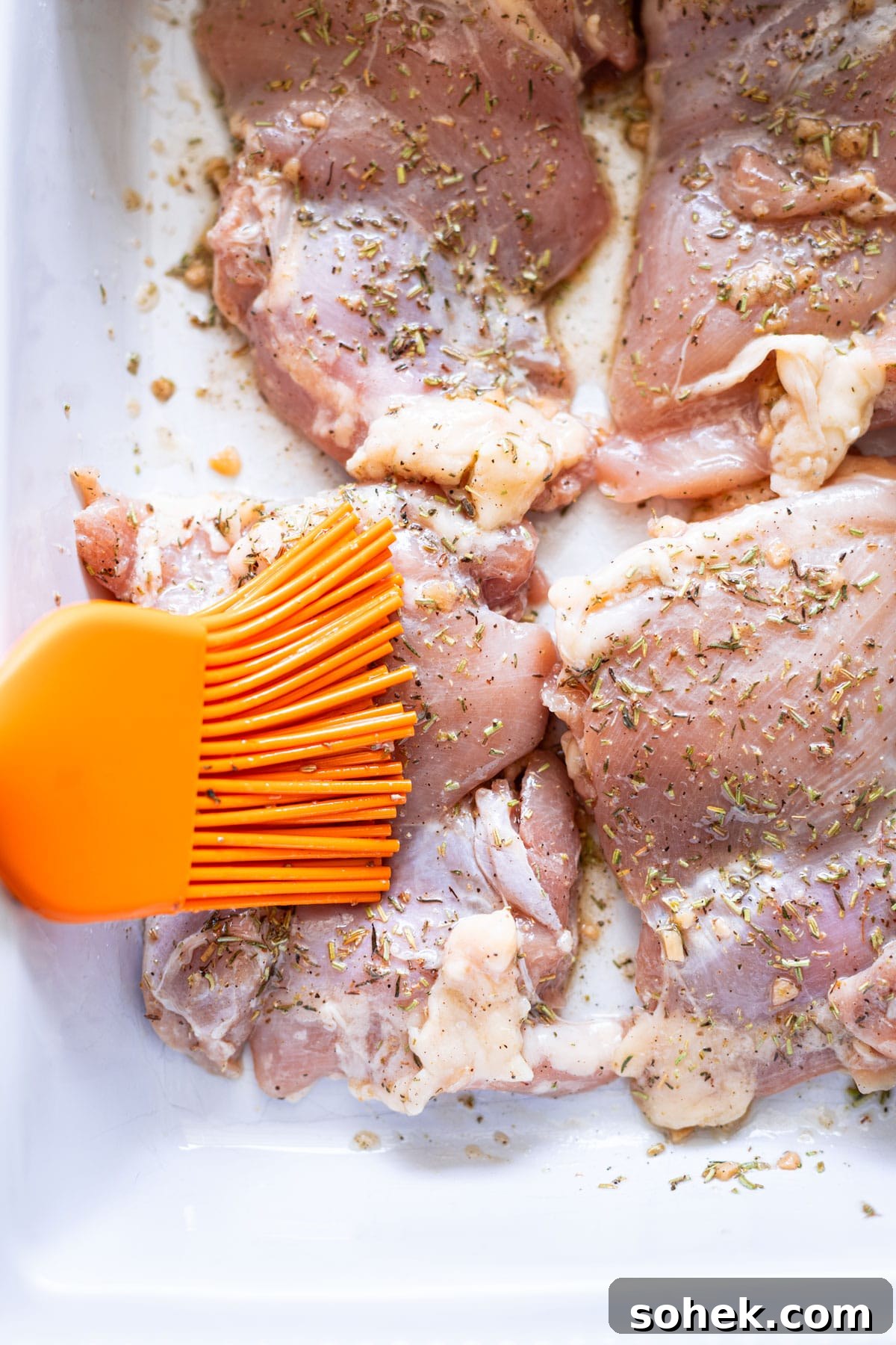 Juicy Smoked Chicken Thighs with Crispy Skin Recipe 7 Four chicken thighs being brushed with seasoning