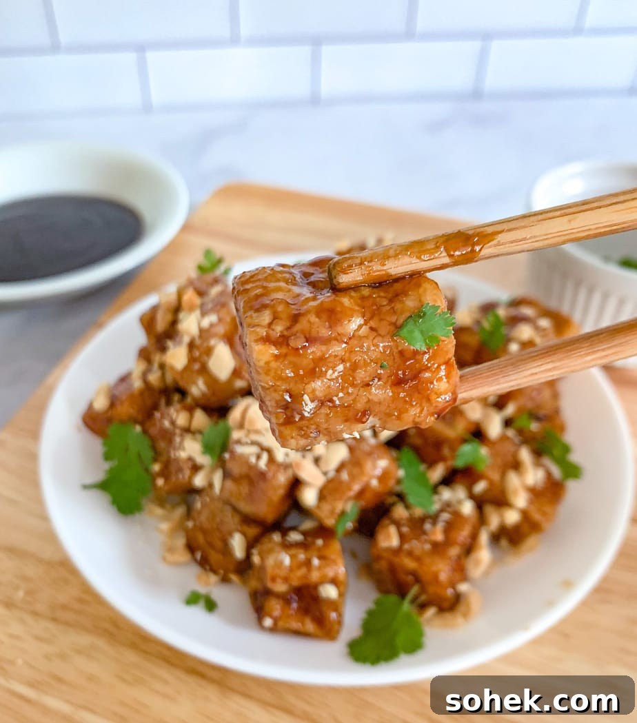 A close up of fried tofu between two chopsticks. 