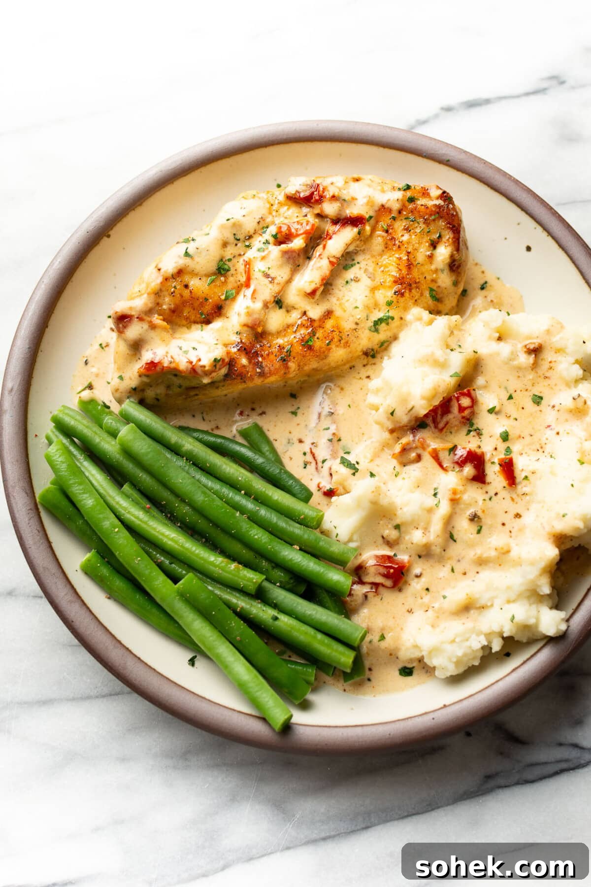 a plate with creamy cajun chicken, green beans, and mashed potatoes