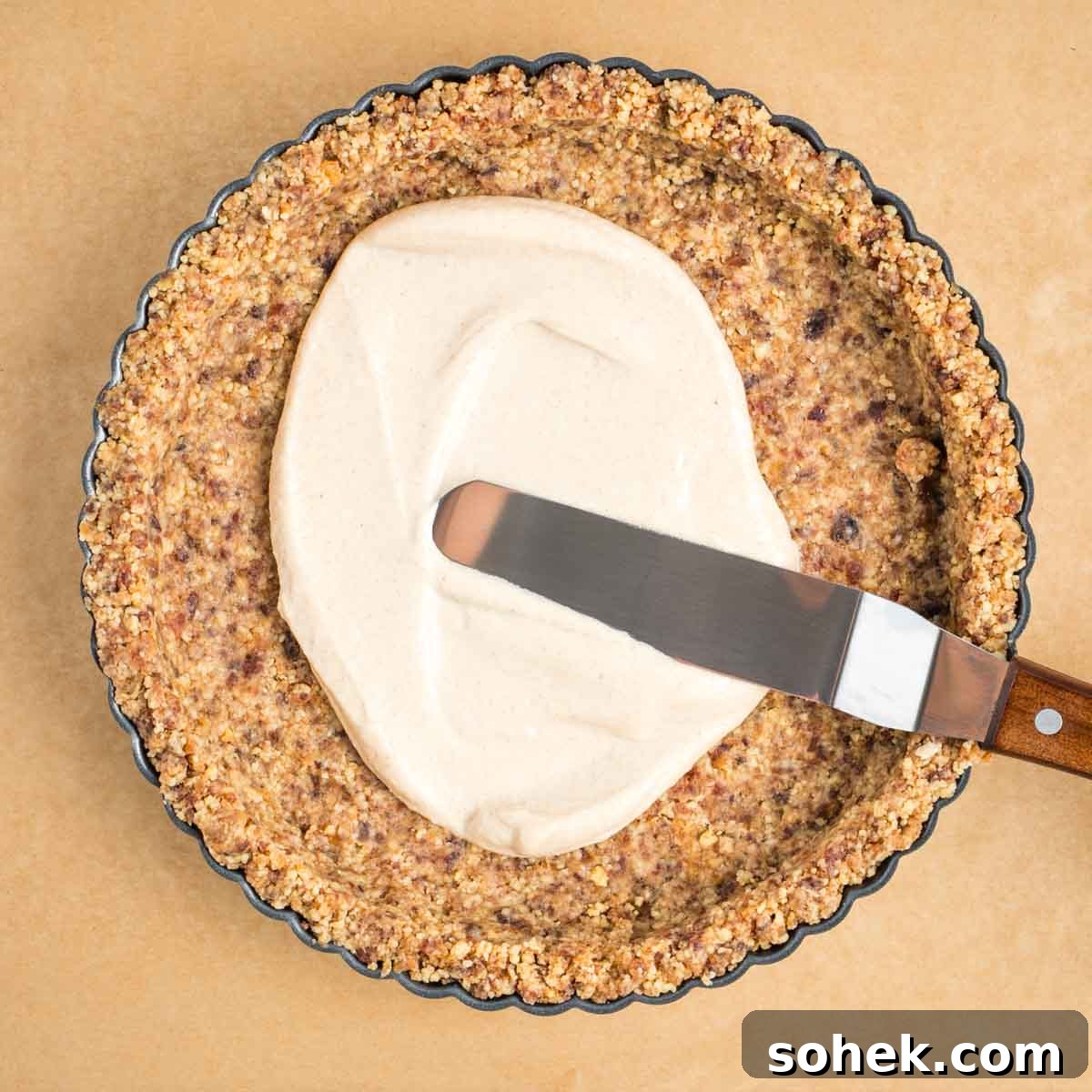 Apple Walnut Tart with Creamy Vegan Cashew Custard Recipe 12 Offset spatula spreading cream into the corners of a walnut crusted in tart pan.