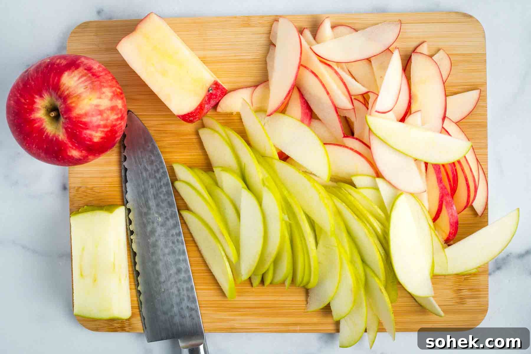 Apple Walnut Tart with Creamy Vegan Cashew Custard Recipe 13 Green and red apples cut into thin slices on a wooden board.