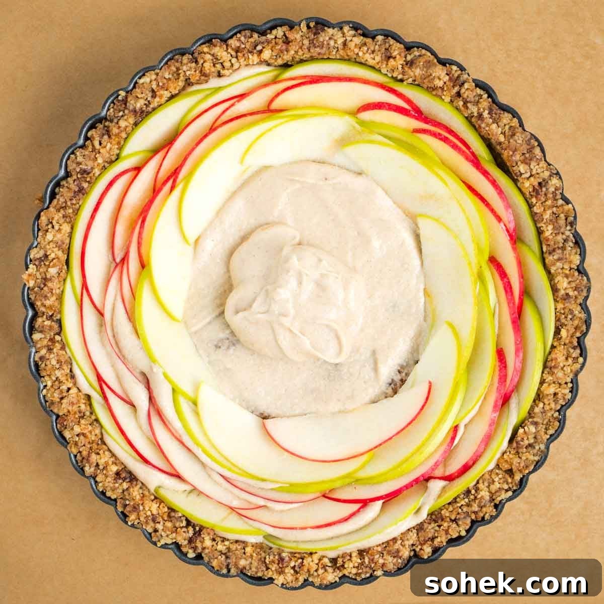 Apple Walnut Tart with Creamy Vegan Cashew Custard Recipe 15 Walnut tart crust with sliced apples going around the edge/towards the center with a dollop of cream inside.