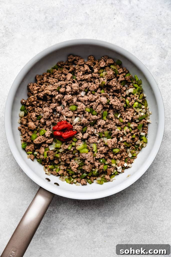 Cheesy Hamburger Rice Casserole Recipe for Comforting Weeknight Meals 4 Ground beef, peppers, onion, and tomato paste in a skillet.