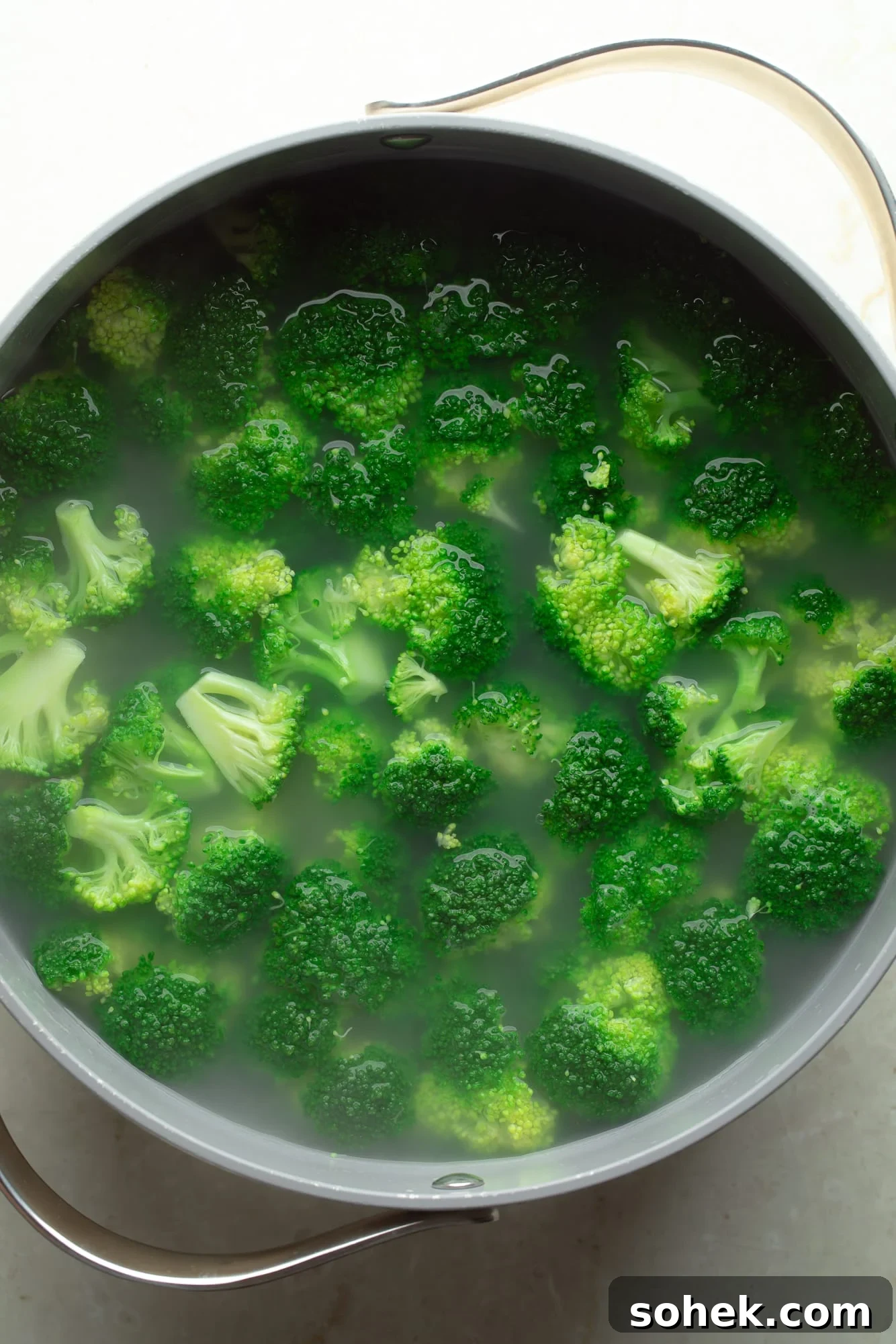 High-Protein Sharp White Mac and Cheese with Broccoli 3 overhead view of broccoli cooking in a pot of hot water.