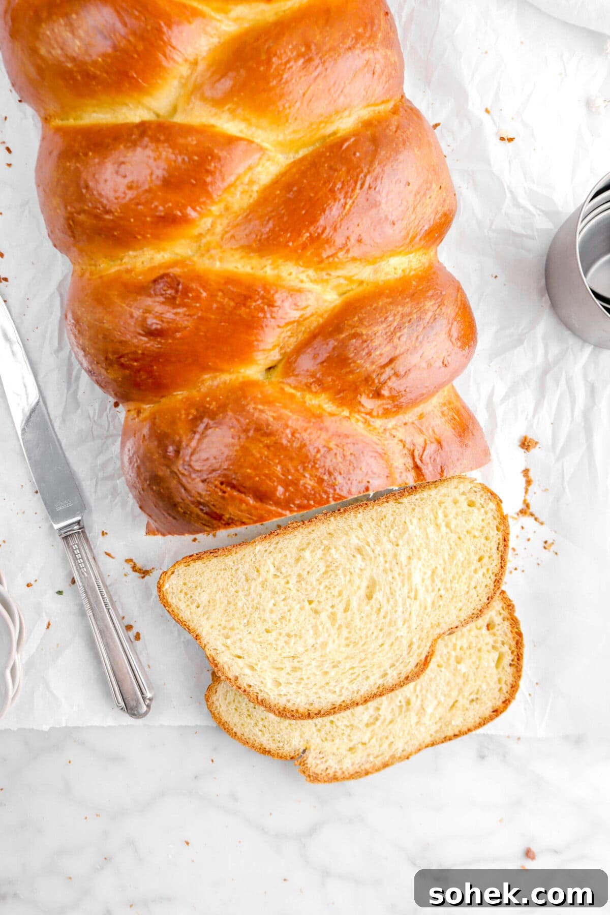 close up overhead shot of two slices of challah in front of loaf
