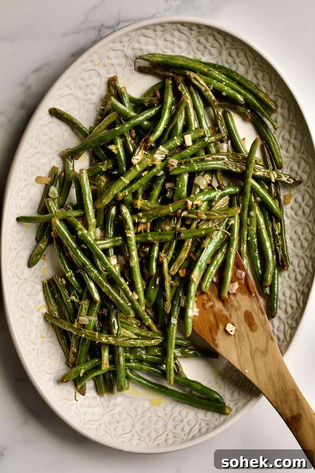 Wooden spatula on a tray of green beans.