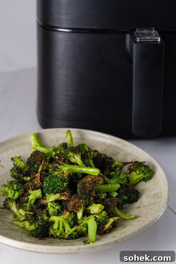 Crispy Air Fryer Roasted Broccoli Recipe 8 Air Fryer Roasted Broccoli in a bowl in front of the air fryer