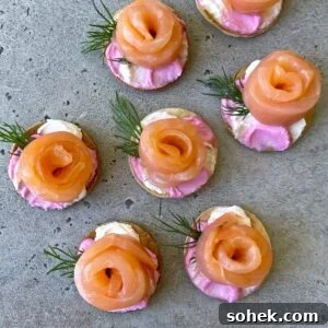 Smoked Salmon Canapés: Classic Recipes and Party Serving Ideas 3 Round tortillas topped with pink and white cream cheese, salmon rosettes, and small sprigs of dill.