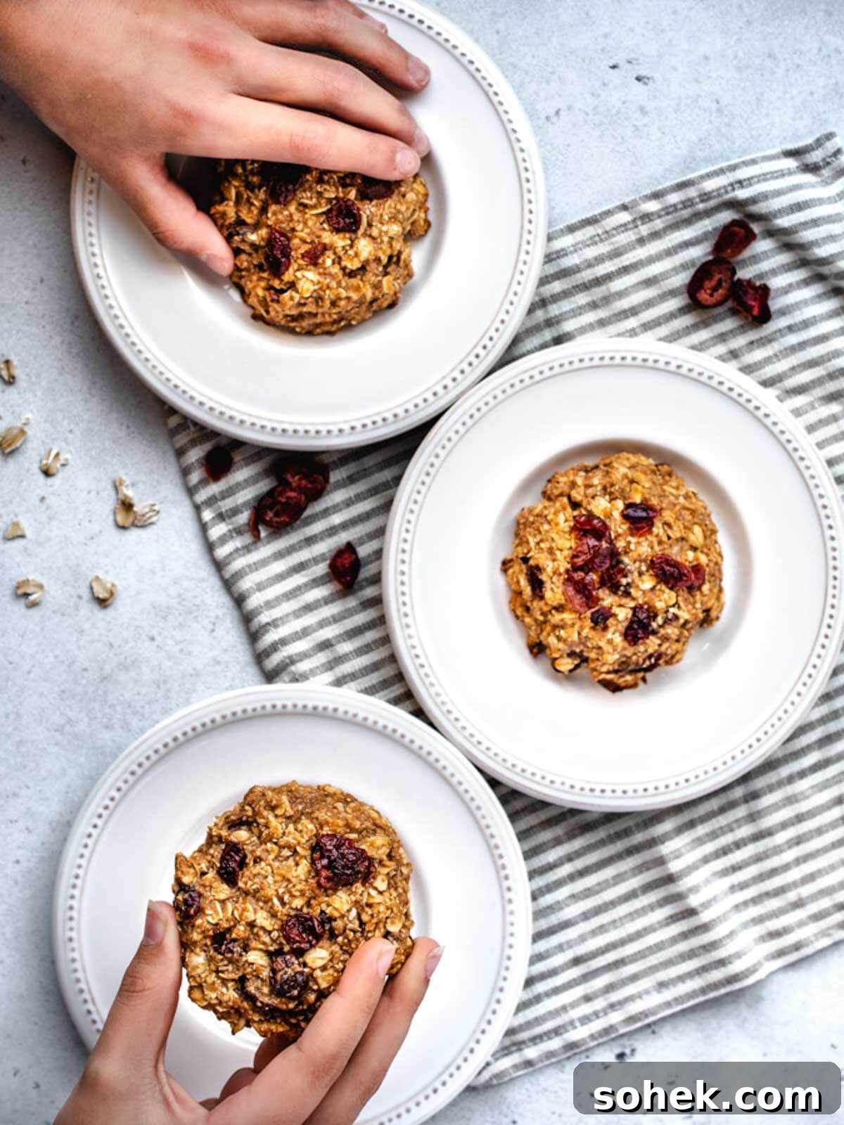 Gluten-Free, Dairy-Free Breakfast Cookies — Make-Ahead Recipe 11 Grabbing for a gluten free dairy free breakfast cookie off a white plate.
