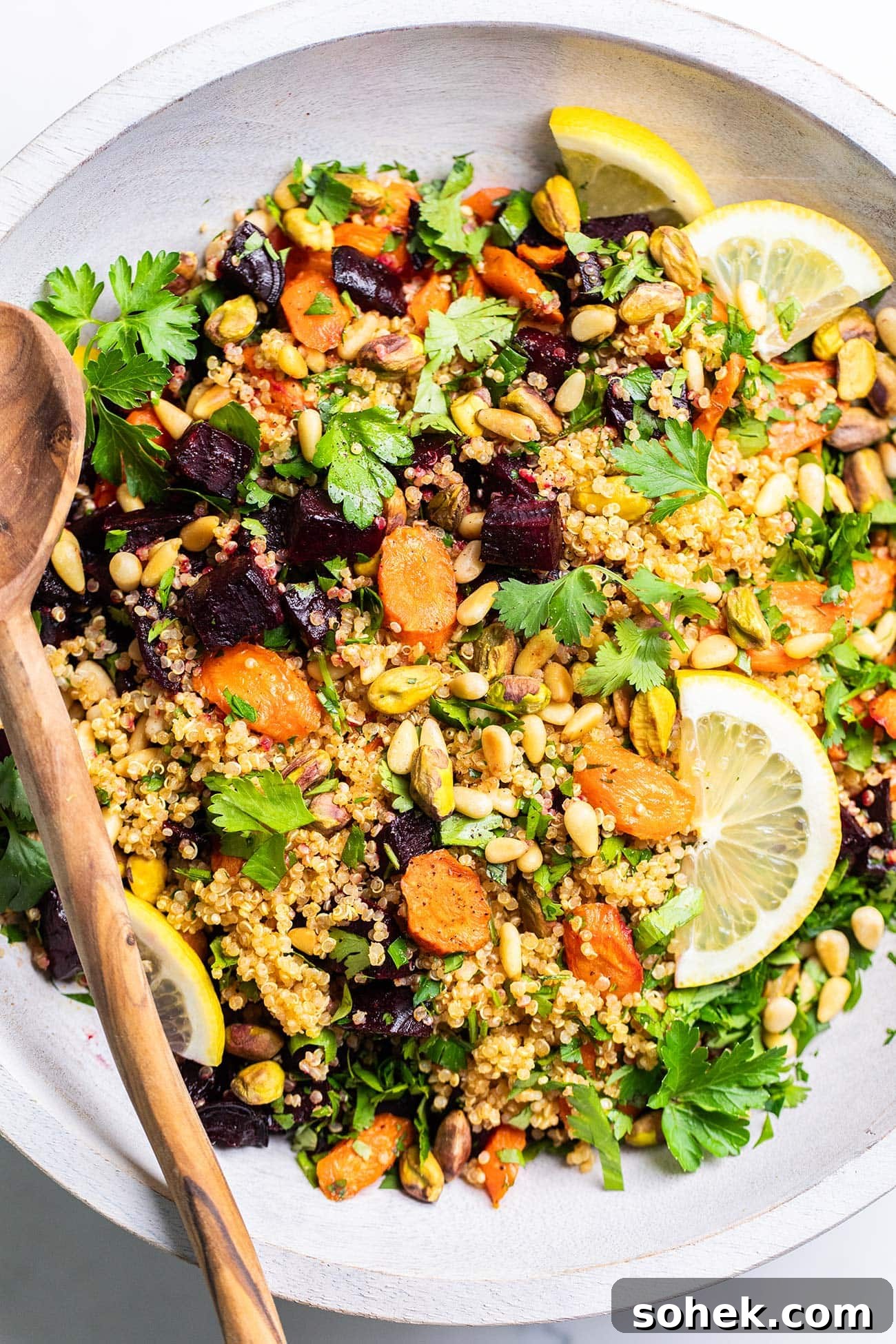 A close up look at a beet quinoa salad with roasted carrots topped with pistachios and pine nuts.