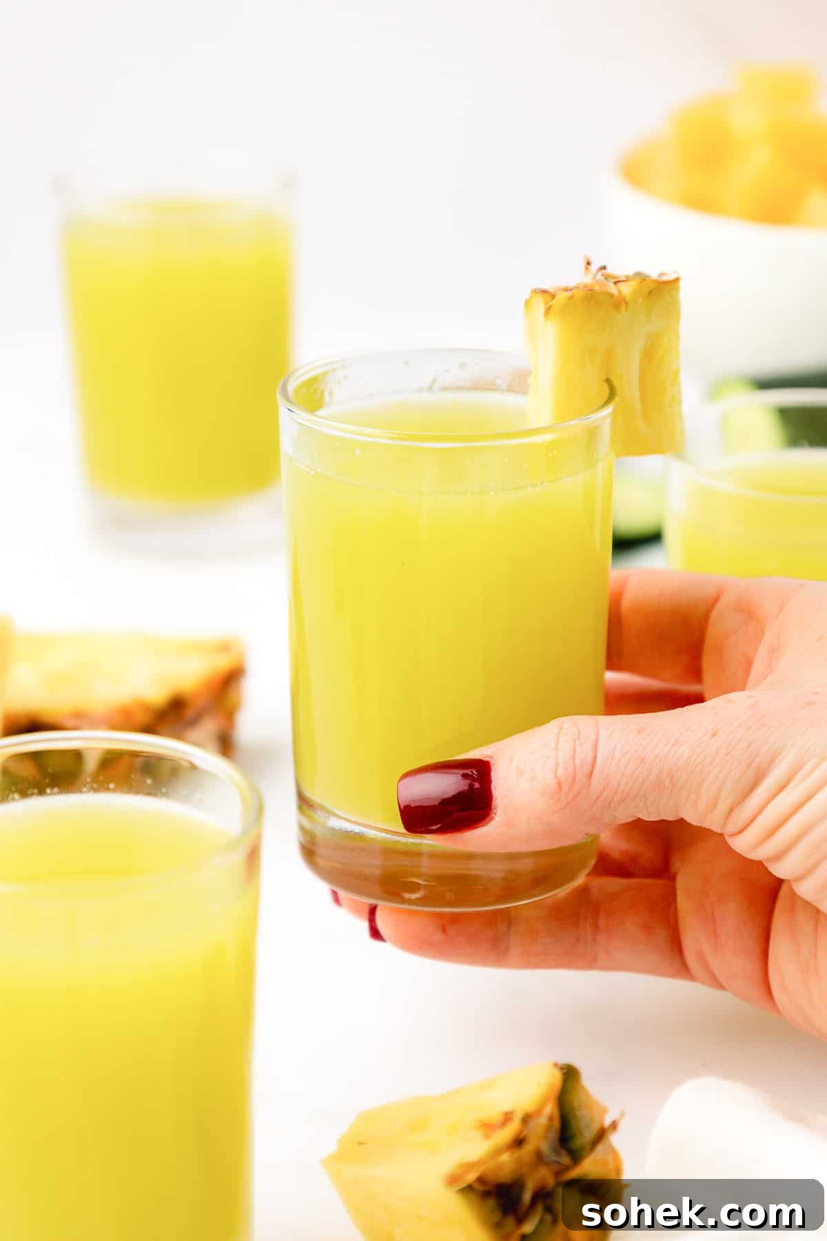 hand holding a glass of pineapple cucumber juice