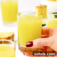 hand holding a glass of pineapple cucumber juice