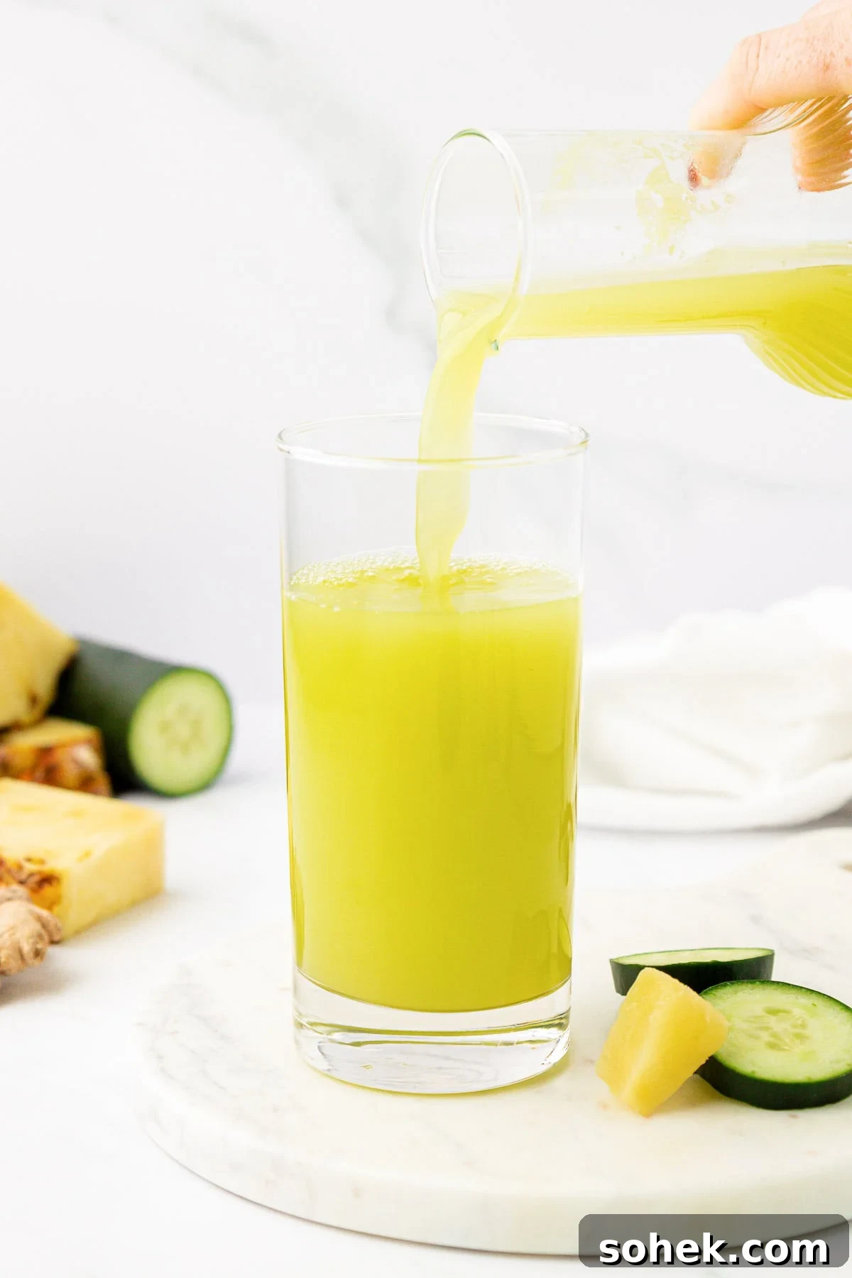 pouring pineapple cucumber juice into a glass