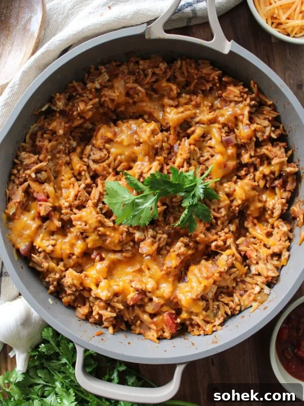 Cheesy taco rice in a skillet garnished with cilantro.