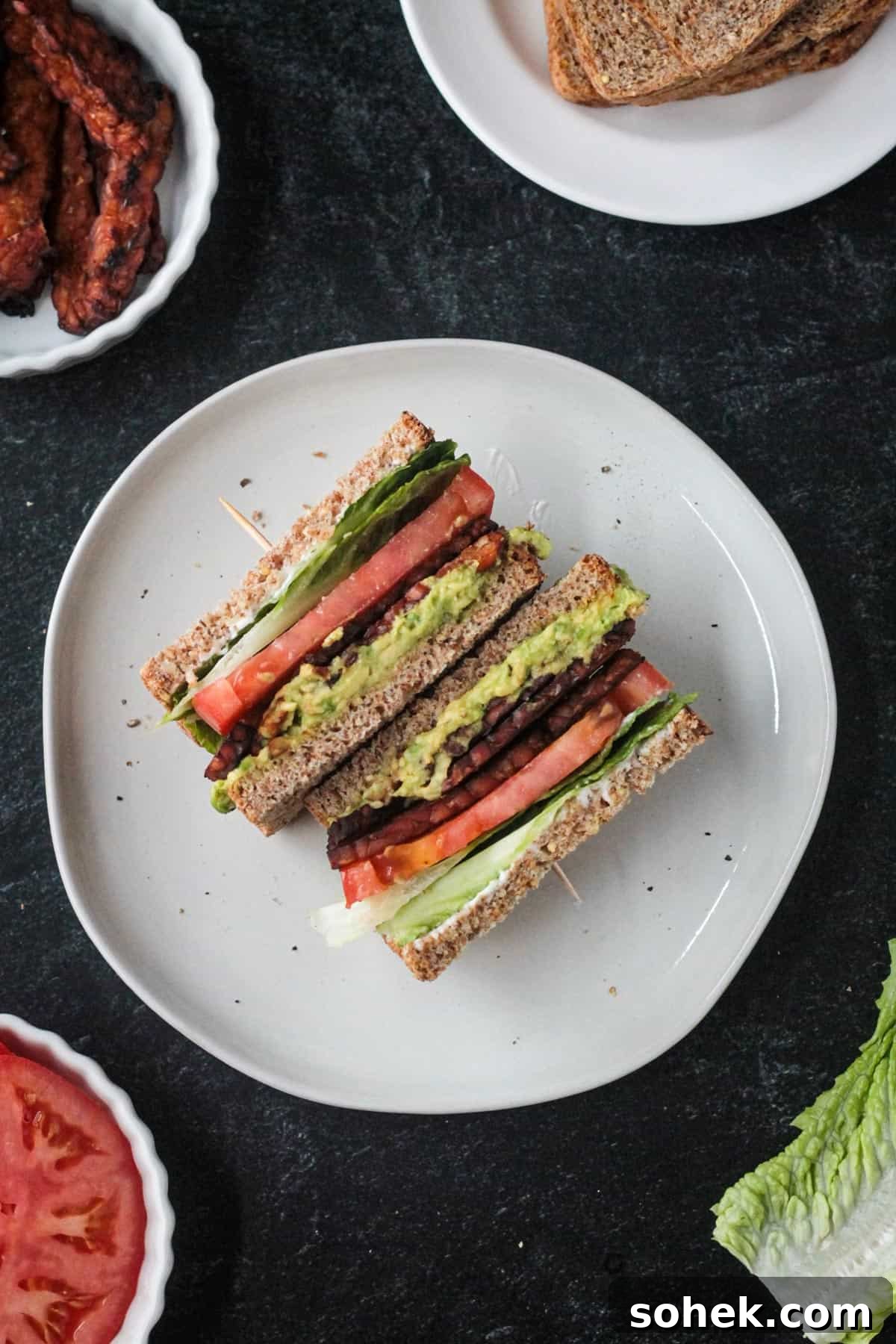 Crispy Vegan BLT Sandwich with Smoky Tempeh Bacon 2 Two halves of a vegan blt sandwich on a plate.