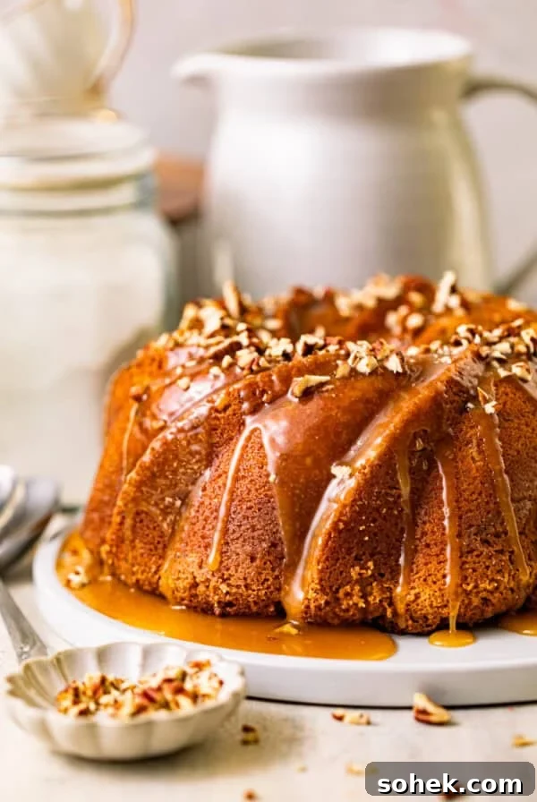 butter pecan pound cake on a serving plate topped with caramel and chopped pecans.