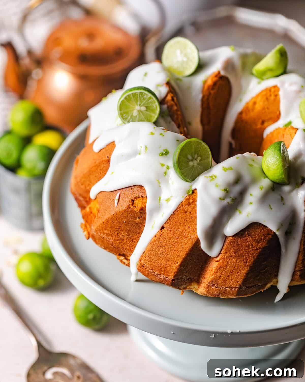 overhead photo of key lime pound cake on a cake stand with fresh key limes.