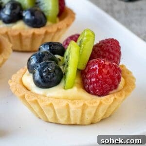 Mini Fresh Fruit Tarts Recipe: Bite-Sized Dessert for Parties 16 Mini fruit tarts on a white plate.