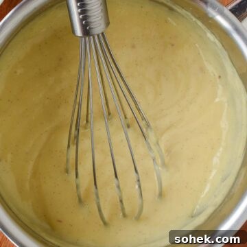 Mini Fresh Fruit Tarts Recipe: Bite-Sized Dessert for Parties 5 Overhead view of thickened pastry cream in a saucepan with a whisk.