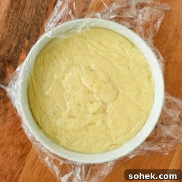 Mini Fresh Fruit Tarts Recipe: Bite-Sized Dessert for Parties 6 Thickened pastry cream in a white bowl covered with plastic wrap.