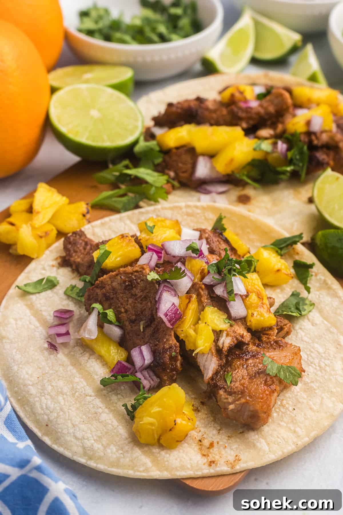 A corn tortilla is filled with cooked meat and pineapple salsa.