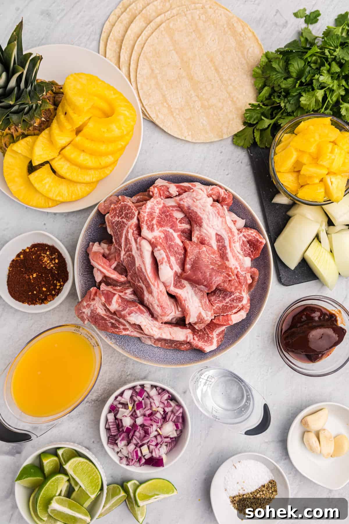 The ingredients for tacos al pastor are placed on a white surface. 