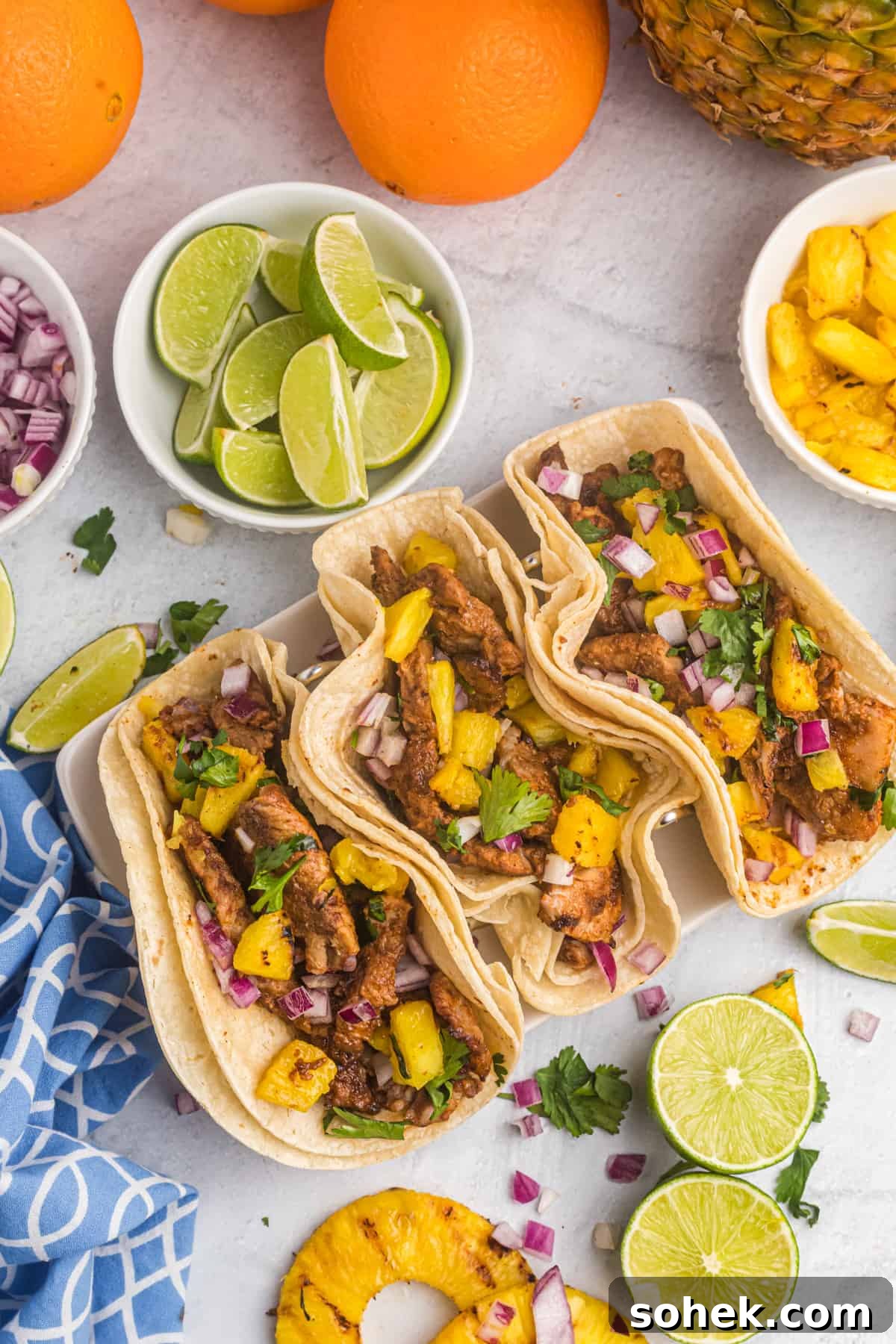Three tacos are placed next to a few different garnishes.