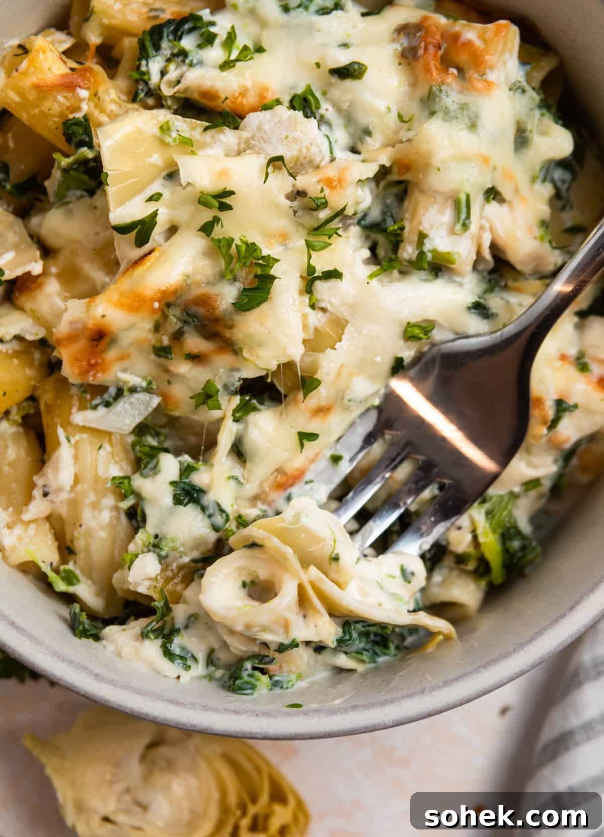 Spinach and Artichoke Chicken Casserole Recipe for Family Meals 2 Bowl of spinach artichoke chicken casserole with forkful of the recipe.