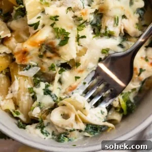 Spinach and Artichoke Chicken Casserole Recipe for Family Meals 12 Chicken spinach and artichoke pasta casserole in dish with fork.