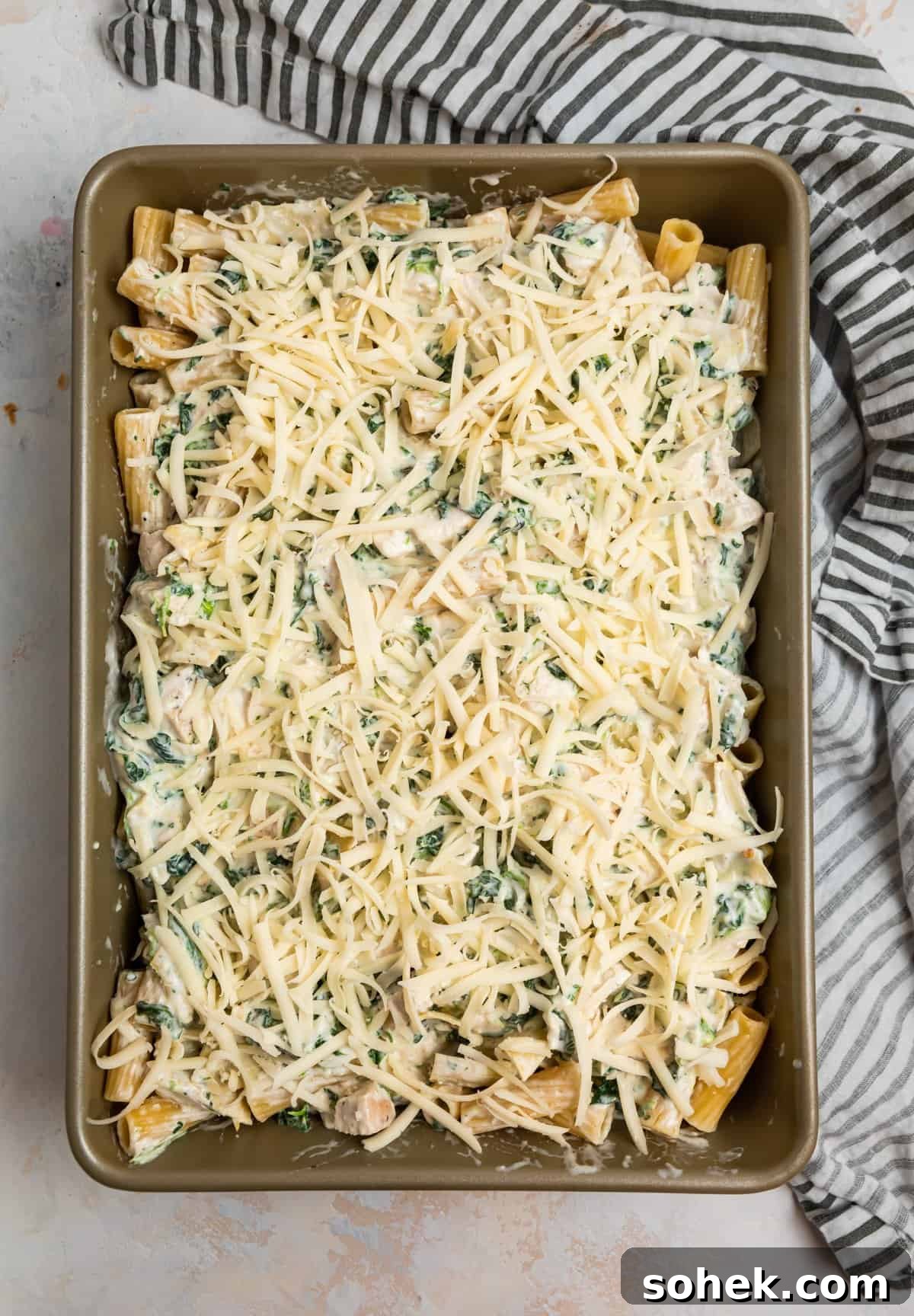 Spinach and Artichoke Chicken Casserole Recipe for Family Meals 9 Casserole dish with shredded cheese on top.