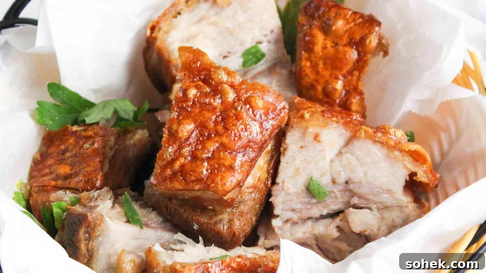 26 Irresistible Air Fryer Game Day Snacks to Serve Guests 18 A basket of crispy roasted pork belly chunks garnished with parsley, served in a white paper-lined wicker basket.