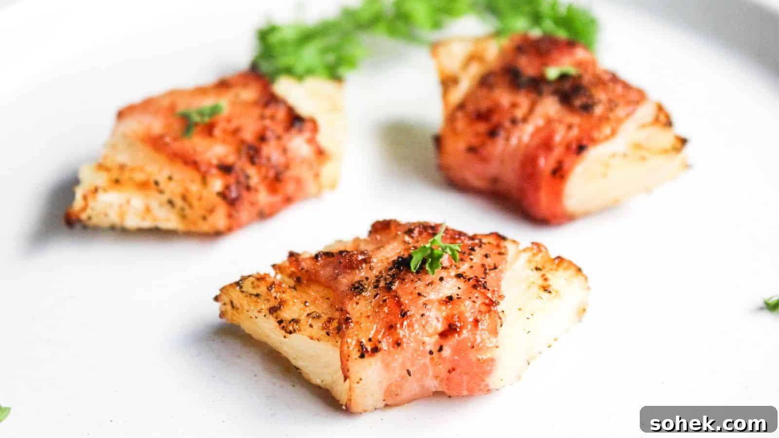 26 Irresistible Air Fryer Game Day Snacks to Serve Guests 28 Bacon wrapped pineapple on a white plate.