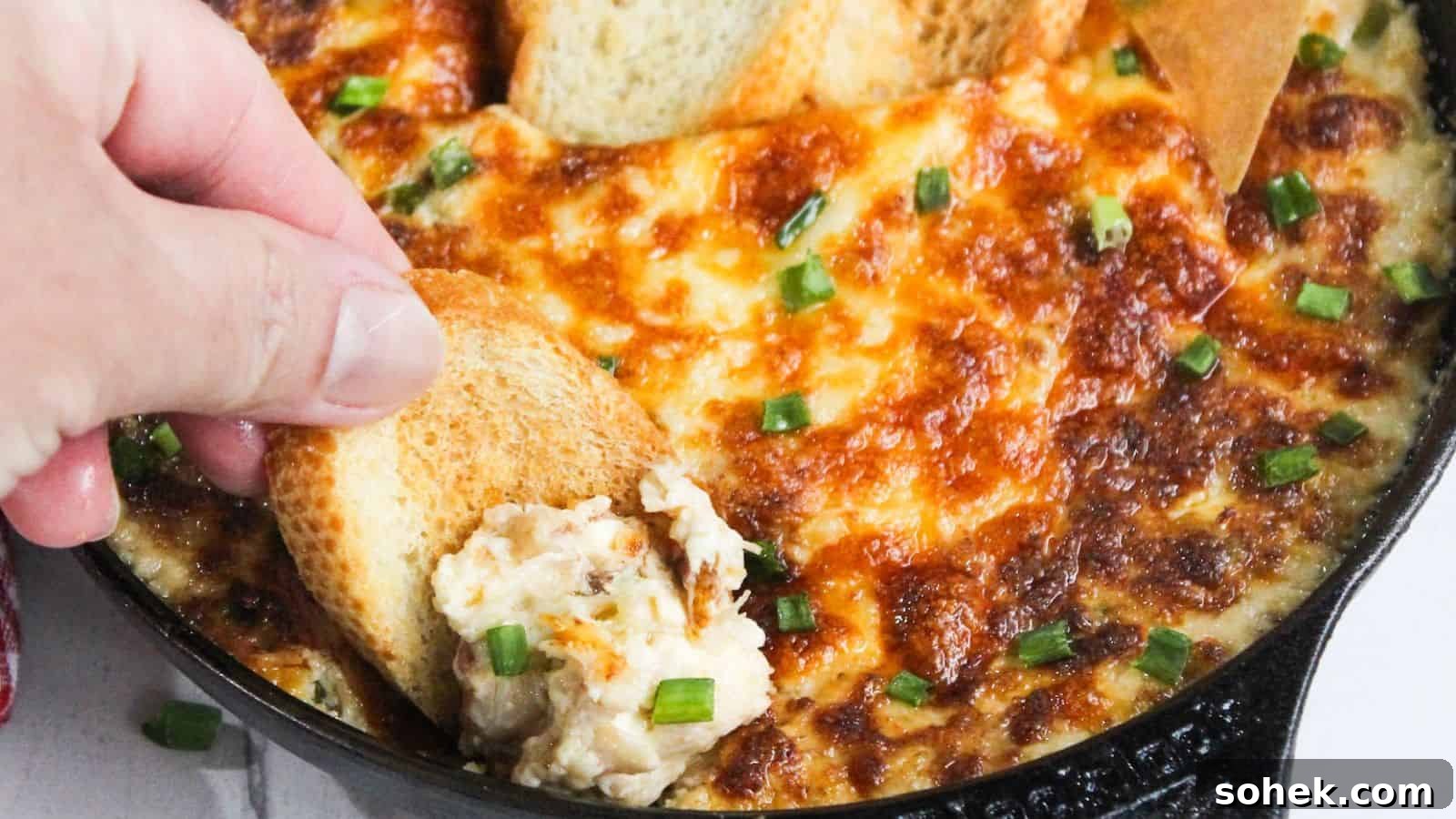26 Irresistible Air Fryer Game Day Snacks to Serve Guests 4 A person dipping a piece of bread into a skillet of cheesy dip.