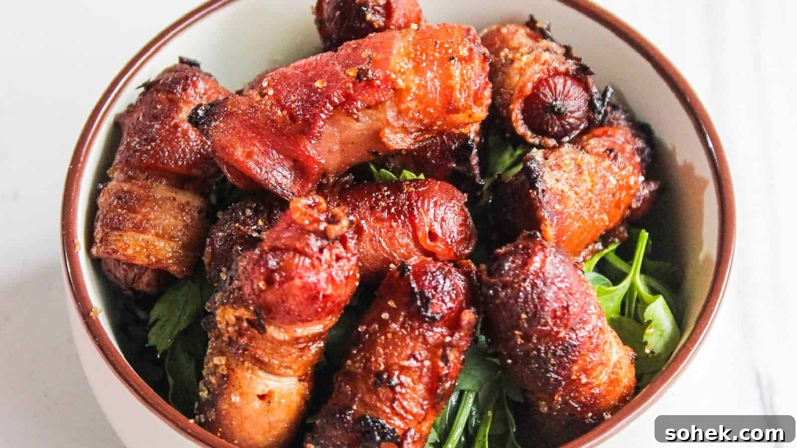 26 Irresistible Air Fryer Game Day Snacks to Serve Guests 5 A bowl of bacon-wrapped cocktail sausages served on a bed of fresh green herbs.