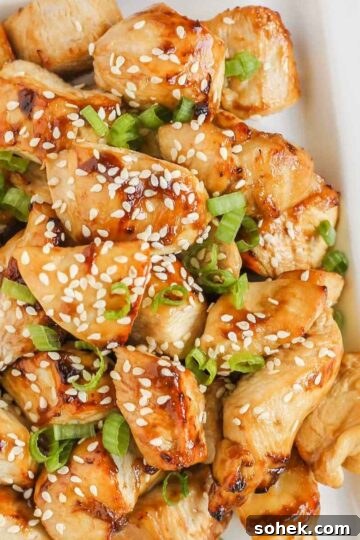 Pieces of air fried teriyaki chicken on a white plate.