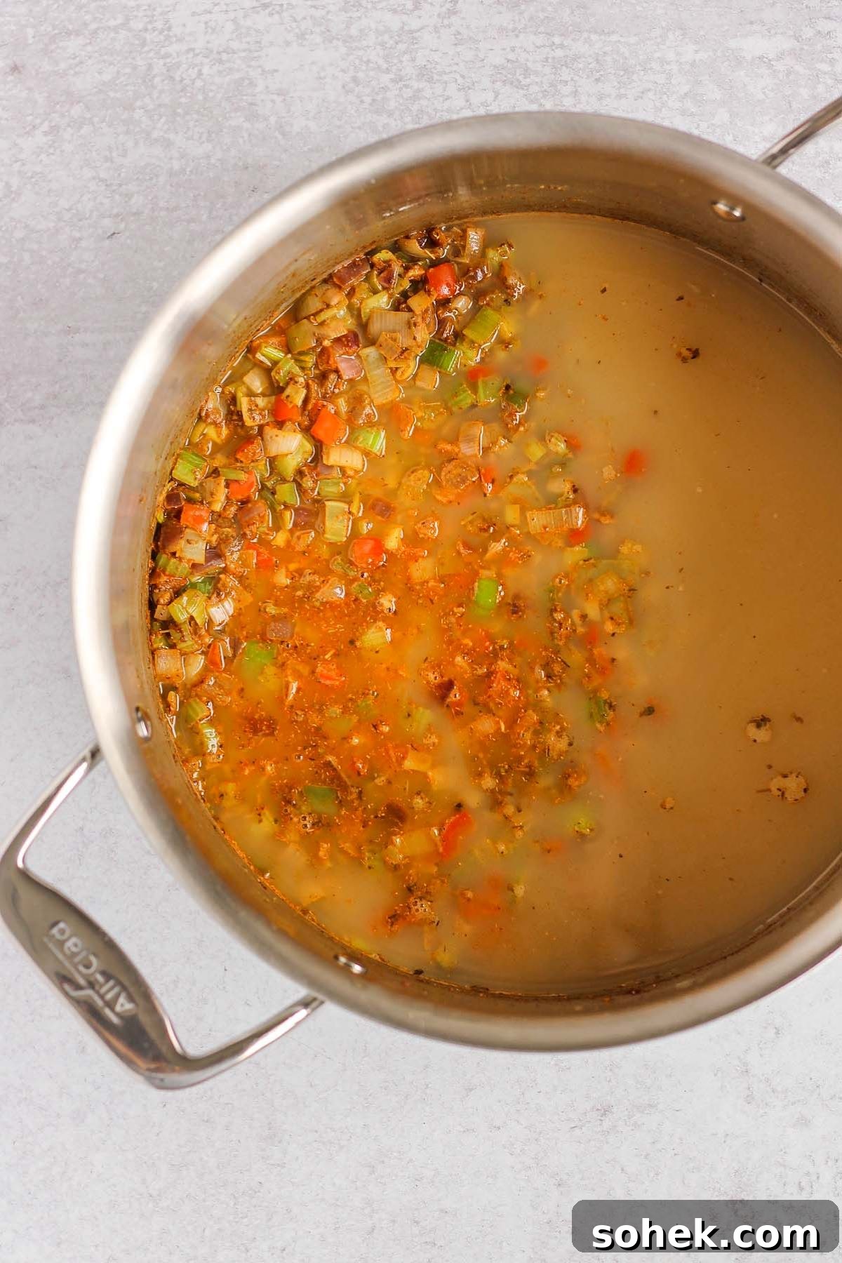 Southwestern Chicken Chili Recipe: Zesty One-Pot Dinner 6 Sauteed veggies and spices plus added broth in a stainless steel pot.