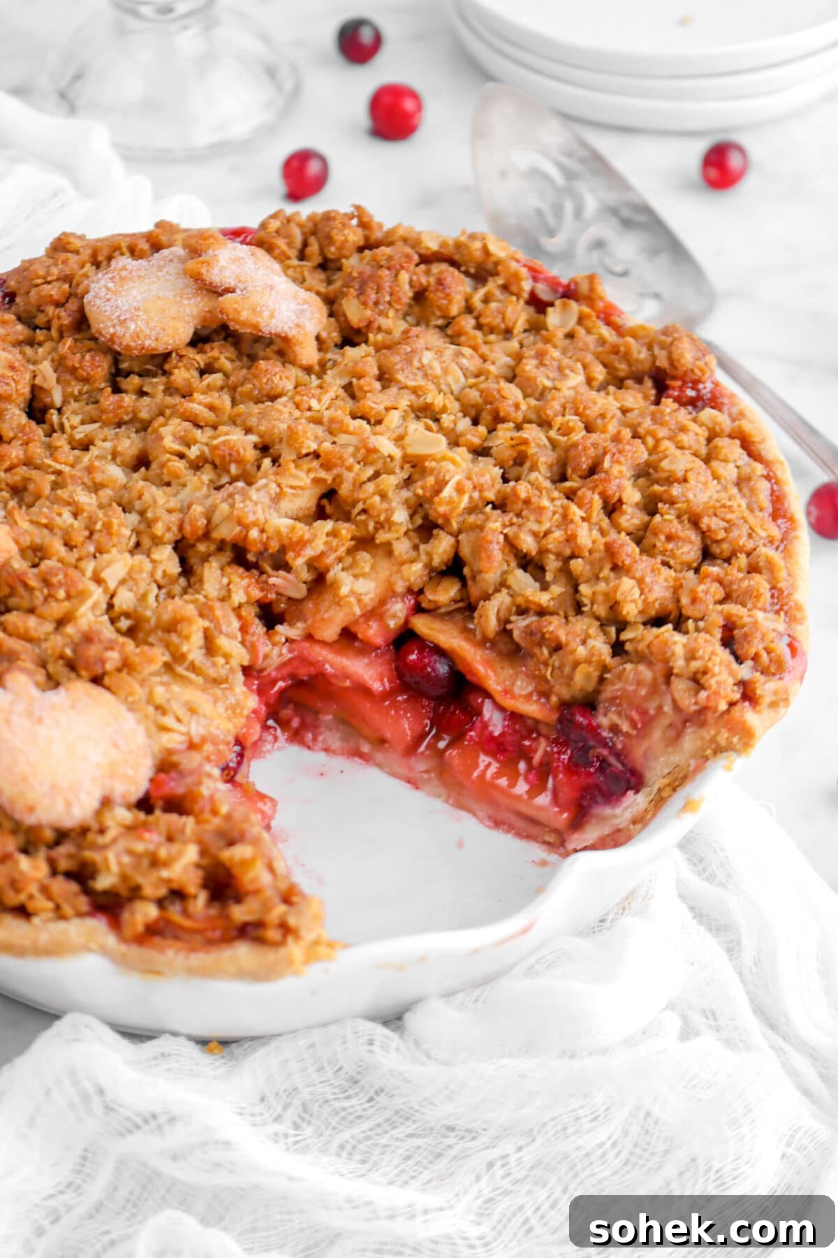 Apple Cranberry Crumble Pie Recipe with Buttery Oat Topping 3 close up of sliced apple cranberry pie in white pie plate.
