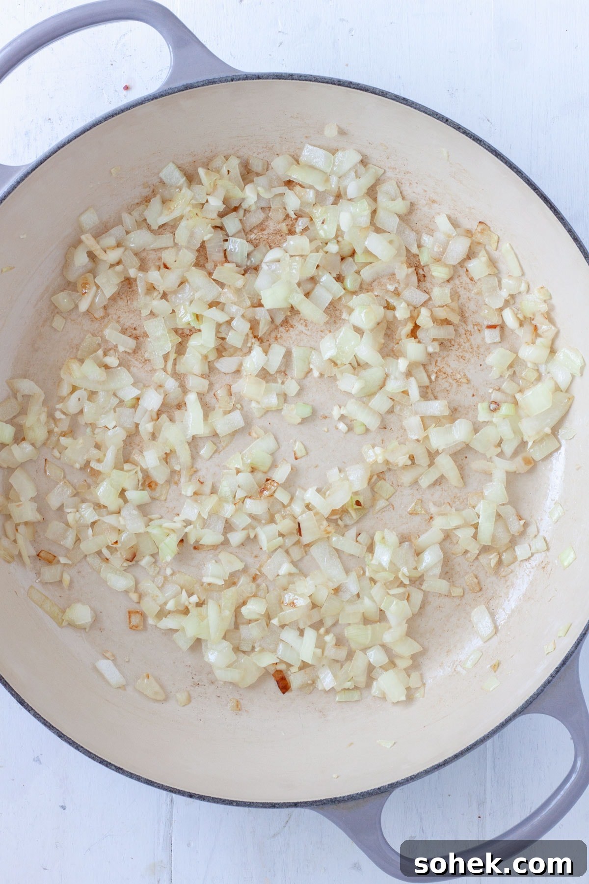 Onions cooking in a large skillet.