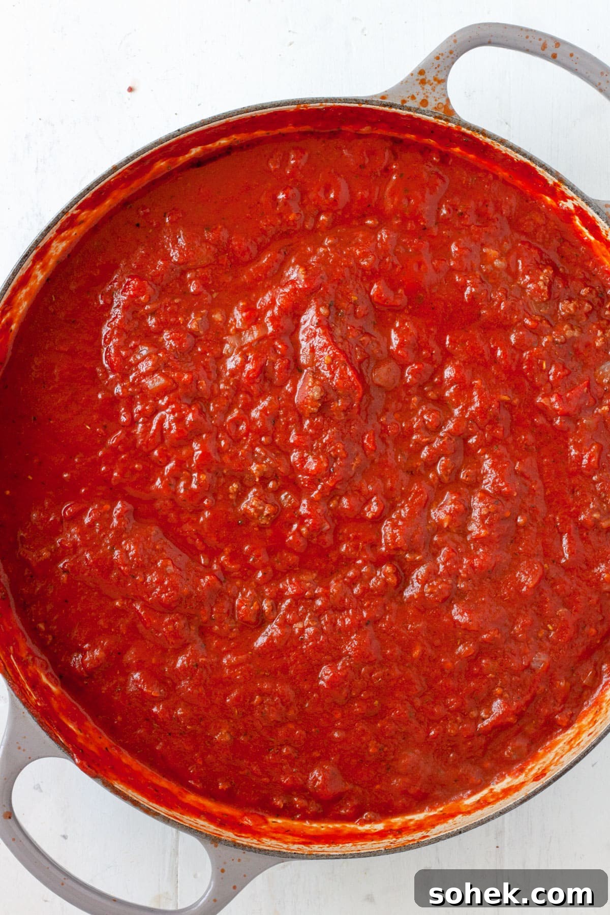 Tomato sauce cooking in a large skillet.