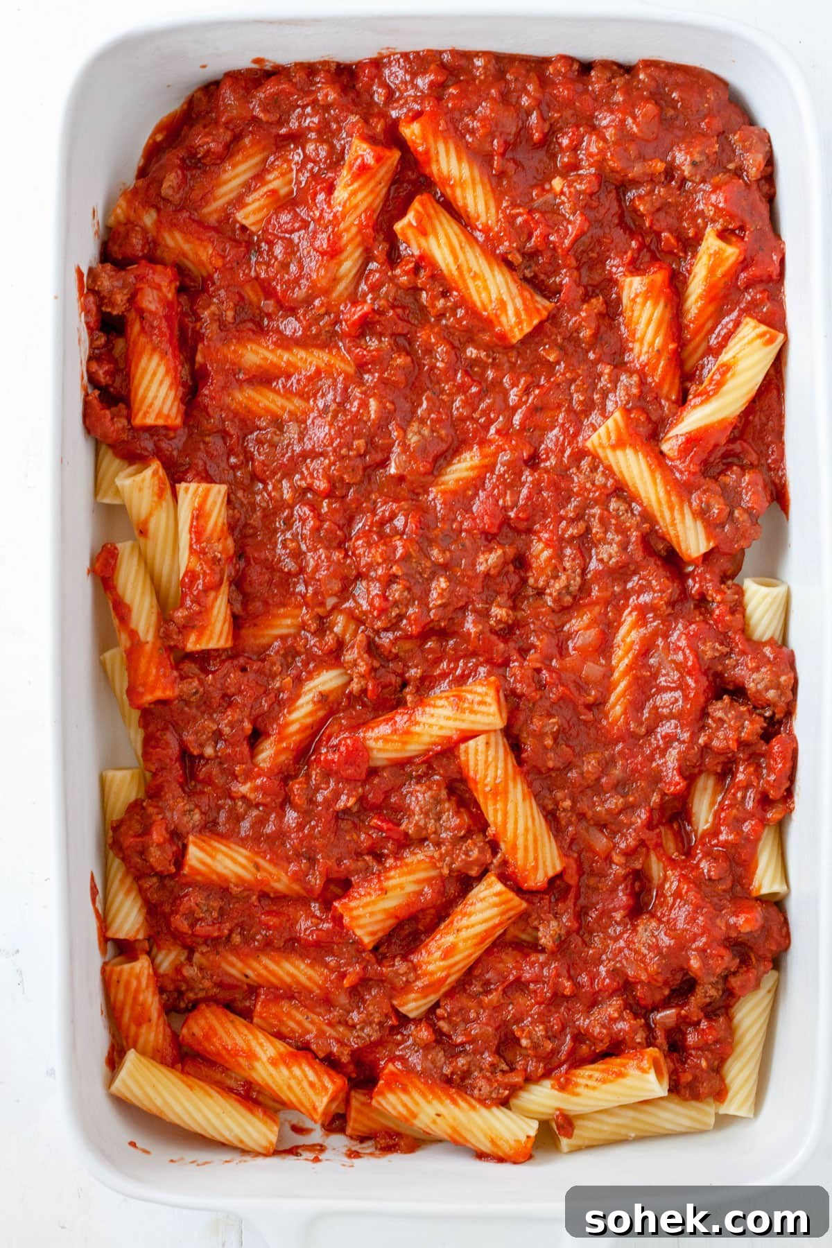 Rigatoni al Forno assembling in a baking dish.