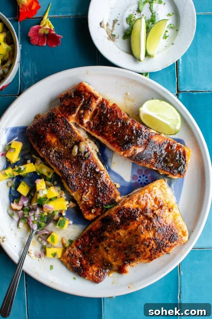 Crispy Salmon Rice Bowl with Fresh Mango Salsa 11 Salmon on a plate with mango salsa on the side on blue tile table.