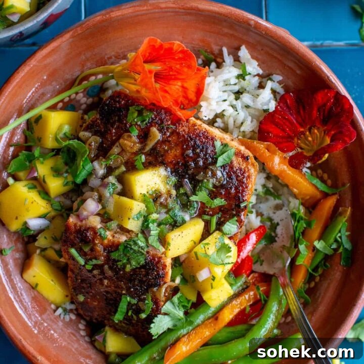 Crispy salmon rice bowls with mango salsa on a blue tile background.