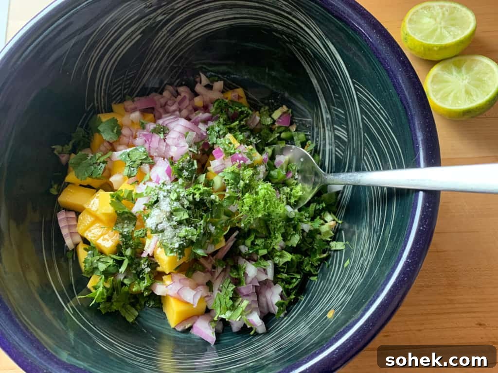 Crispy Salmon Rice Bowl with Fresh Mango Salsa 6 mango salsa in a bowl being mixed with a spoon.