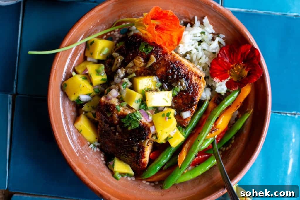 Crispy Salmon Rice Bowl with Fresh Mango Salsa 10 A bowl of salmon on top of rice with green beans and peppers