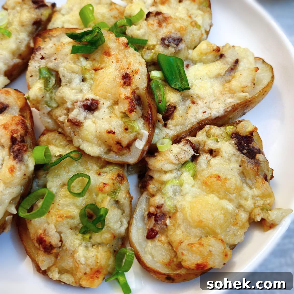 A white plate of cooked stuffed potato skins.