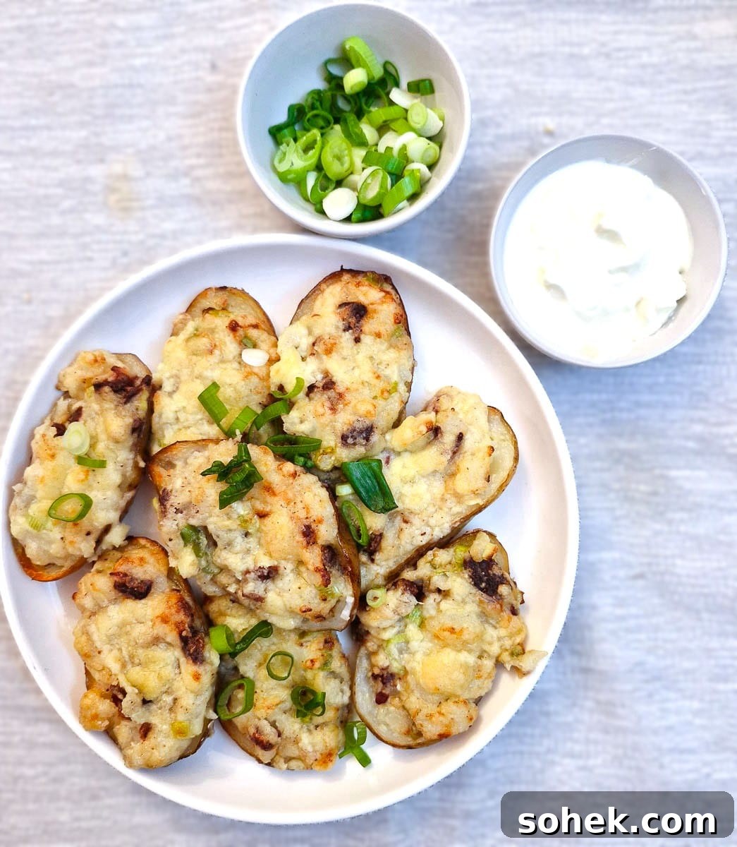 Stuffed potato skins on a white plate with a dish of sour cream and a dish of chopped spring onions.