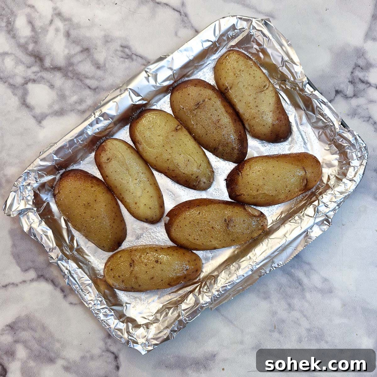Baked potato skins arranged upside down on a baking tray.