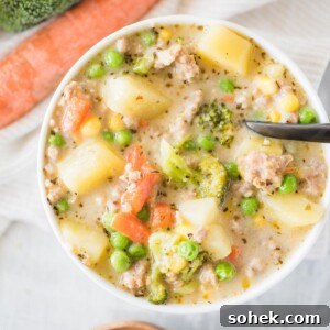 Hearty Italian Sausage and Potato Soup Recipe 5 White bowl full of soup with a black spoon on a table with carrots and broccoli