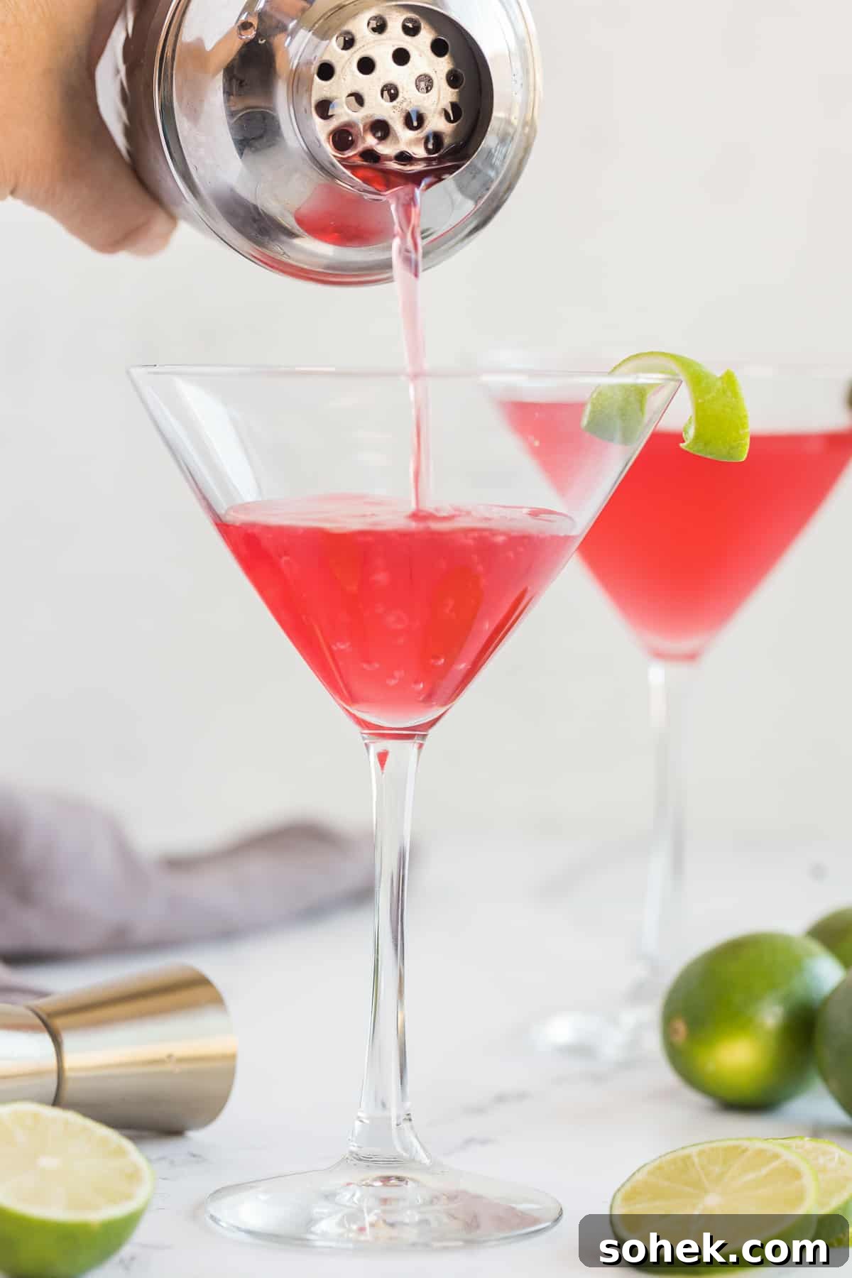Classic Cosmopolitan Cocktail Recipe: How to Mix a Perfect Cosmopolitan 9 A cosmopolitan pouring out of a cocktail shaker into a martini glass.