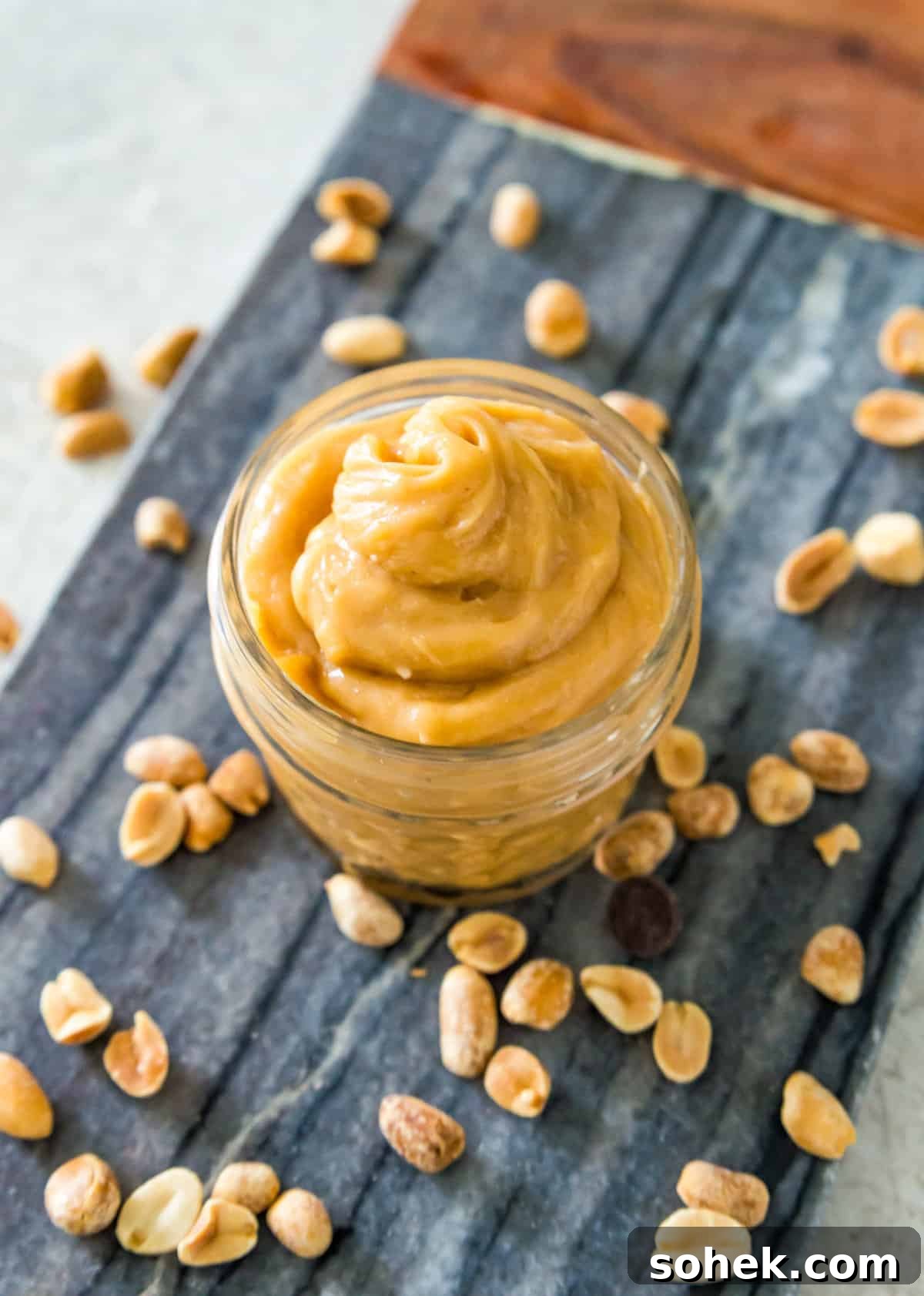 Peanut Butter Mousse with 4 Ingredients — Quick Creamy Dessert 2 A small clear jar filled with peanut butter mousse on a serving tray with peanuts around it.